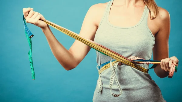 Fitness girl measuring her body with tapes — Stock Photo, Image