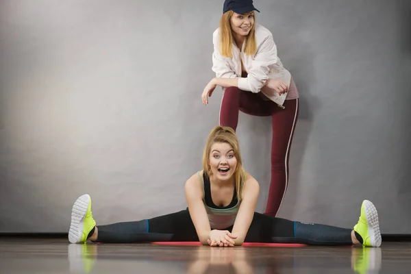 Woman in sportswear stretching legs with trainer — Stock Photo, Image