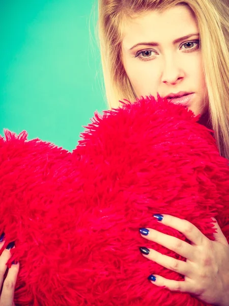 Mujer triste sosteniendo almohada roja en forma de corazón — Foto de Stock