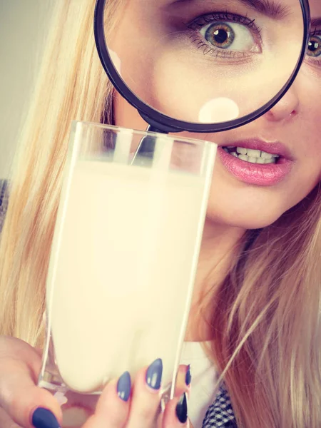 Женщина смотрит на молоко через увеличительное стекло — стоковое фото