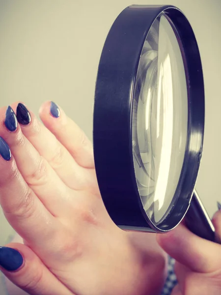 Vrouw op zoek naar nagels door vergrootglas — Stockfoto