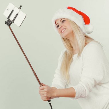 Santa şapka alarak fotoğrafını selfie stick kullanarak kız