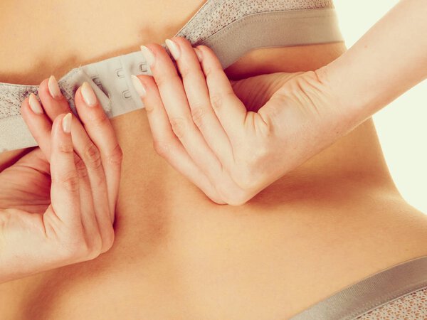 Симпатичная стройная женщина снимает серый лифчик
