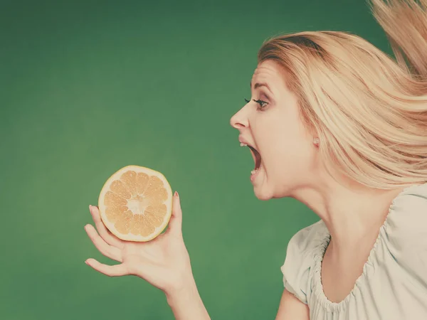 Frau mit offenem Mund hält Grapefruit in der Hand — Stockfoto