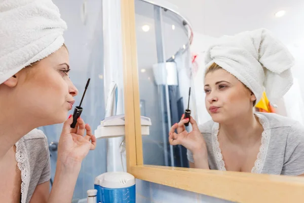 Mujer en el baño aplicando rímel en las pestañas — Foto de Stock