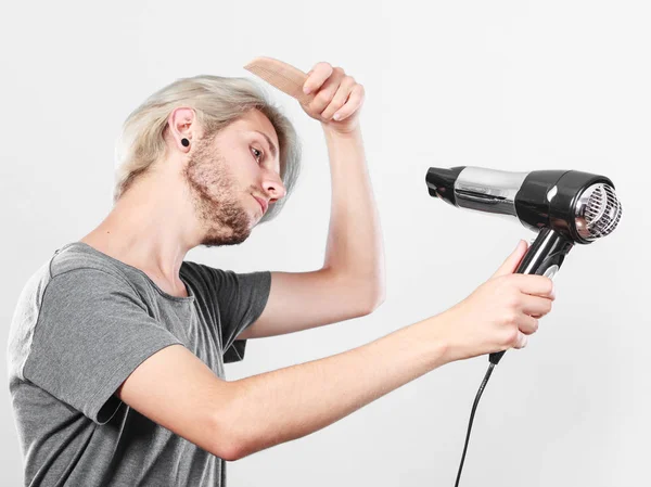 Jovem homem secando o cabelo com secador de cabelo — Fotografia de Stock