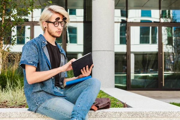 Hipster guy with tablet sitting on ledge — Stock Photo, Image
