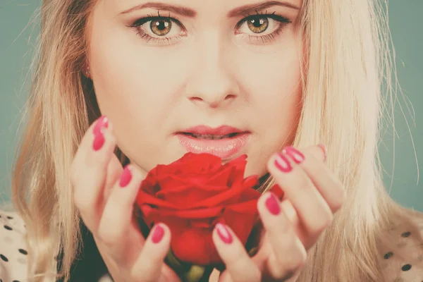 Kırmızı gül yakınındaki yüz tutan Closeup kadın.