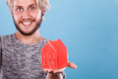 Gülümseyen adam küçük kırmızı ev tutan