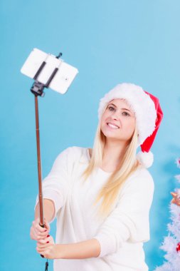 Santa şapka alarak fotoğrafını selfie stick kullanarak kız
