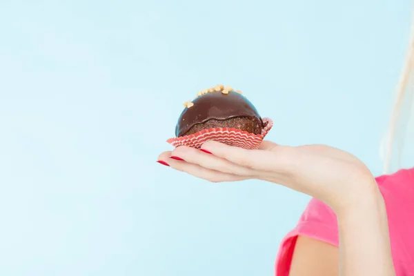 Donna mano che tiene il cioccolato cupcake in procinto di mordere — Foto Stock