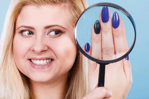 Woman looking at nails through magnifying glass — Stock Photo, Image