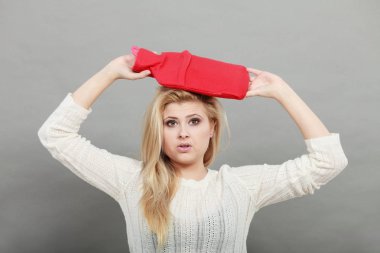 Kırmızı sıcak su şişesi üzerinde kafa tutan kadın