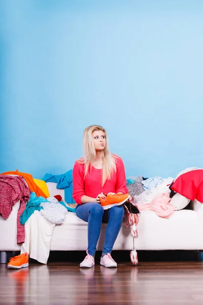 Woman does not know what to wear sitting on couch