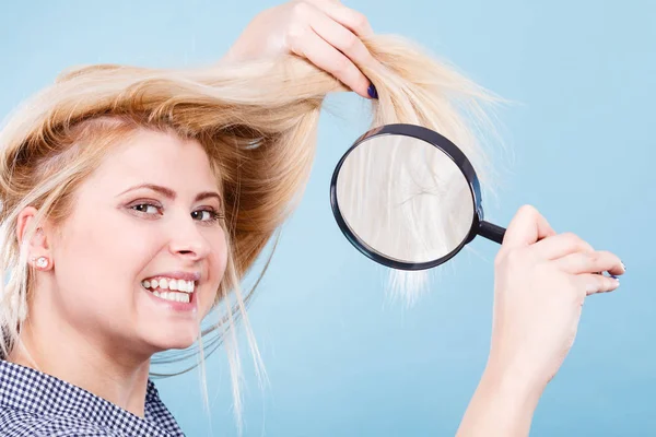 Woman looking at hair through magnifying glass — Stock Photo, Image
