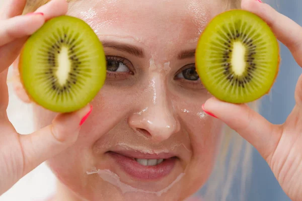 Wanita memiliki topeng gel di wajah memegang kiwi — Stok Foto