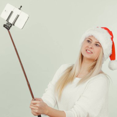 Santa şapka alarak fotoğrafını selfie stick kullanarak kız
