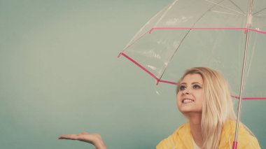 Hava kontrol şemsiye tutan yağmurluk giyen kadın
