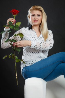 Koltukta oturan kız kırmızı gül, karanlık üzerinde tutar..