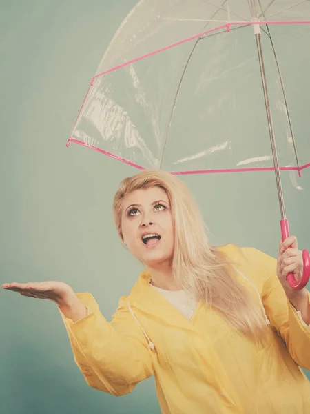 Mujer vistiendo impermeable sosteniendo paraguas comprobando el clima — Foto de Stock