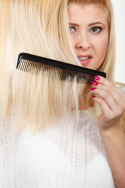 Mulher loira escovando seu cabelo longo com pente — Fotografia de Stock