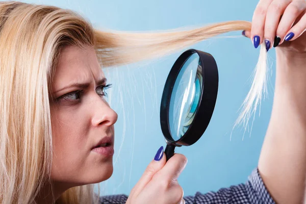 Woman looking at hair through magnifying glass — Stock Photo, Image