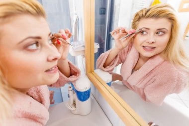 Kaşlarını cımbızla temizleyen kadın.