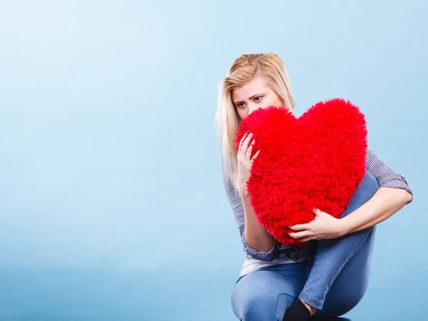 Mujer triste sosteniendo almohada roja en forma de corazón — Foto de Stock