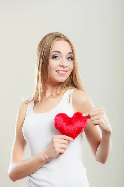 Mujer sonriente sosteniendo el símbolo de amor corazón rojo — Foto de Stock