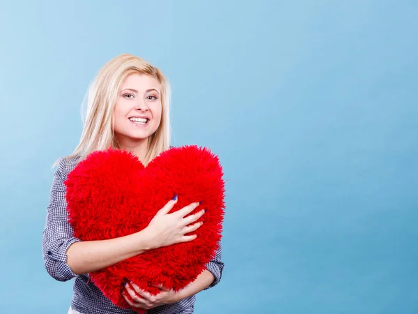 Mujer feliz sosteniendo almohada roja en forma de corazón —  Fotos de Stock