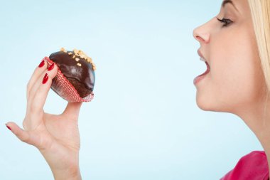 Çikolatalı kek tutan kadın ısırmak üzere.