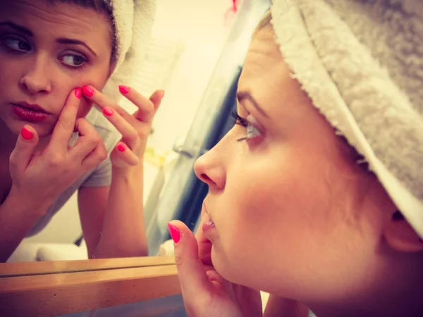 Mujer mirando en el espejo tratando con el acné — Foto de Stock