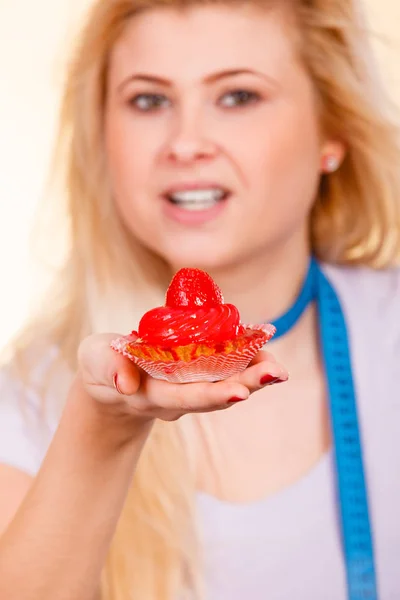 Woman with measuring tape holding sweet cupcake — Stock Photo, Image