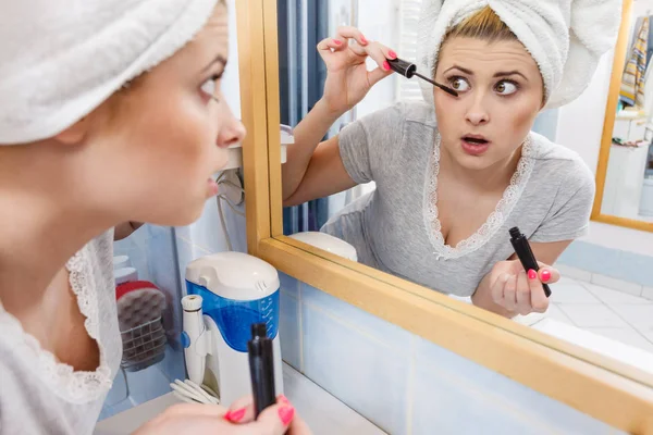 Mujer en el baño aplicando rímel en las pestañas —  Fotos de Stock