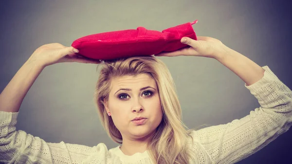 Woman holding red hot water bottle on head