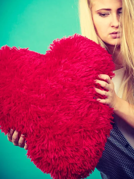 Mujer triste sosteniendo almohada roja en forma de corazón — Foto de Stock