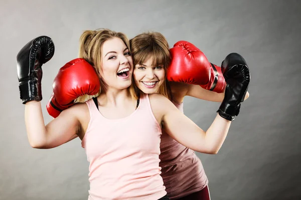 Two women friends wearing boxing gloves