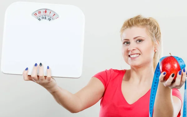 Woman holding apple,measuring tape and weight machine — Stock Photo, Image