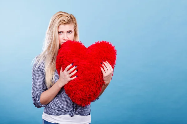 Mujer triste sosteniendo almohada roja en forma de corazón — Foto de Stock