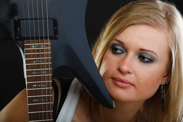 Femme blonde tenant une guitare électrique, fond noir — Photo
