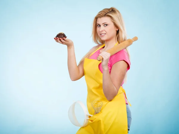 Mulher segurando cupcake, rolo, escorredor vestindo avental — Fotografia de Stock