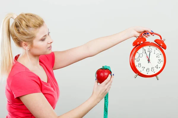 Mujer feliz sosteniendo reloj, manzana y cinta métrica — Foto de Stock