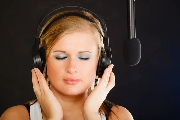 女性がスタジオでヘッドフォンのマイクに歌う — ストック写真