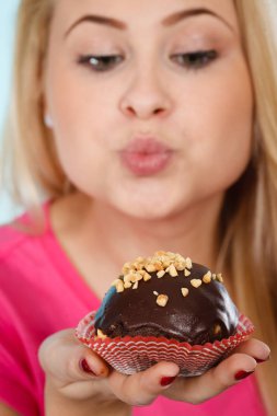 Çikolatalı kek tutan kadın ısırmak üzere.