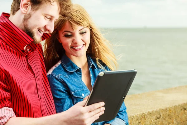 Young couple with tablet by seaside outdoor