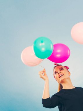 Tatlı gülümseyen kız renkli balonlar tutar.