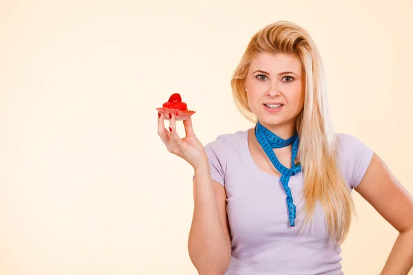 Frau mit Maßband hält süßen Cupcake — Stockfoto