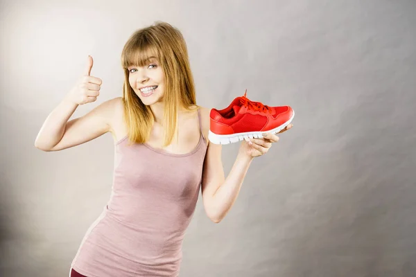 Happy woman presenting sportswear trainers shoes — Stock Photo, Image