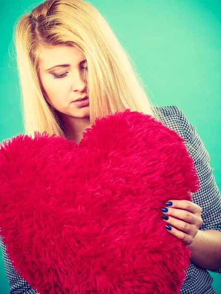 Mujer triste sosteniendo almohada roja en forma de corazón — Foto de Stock