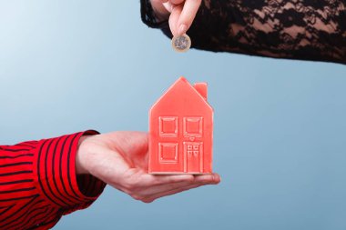 İnsanlar elleriyle küçük ev ve gümüş sikke.